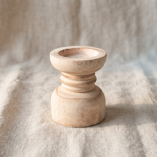 Turned wooden candle holder on light natural linen, 45-degree view